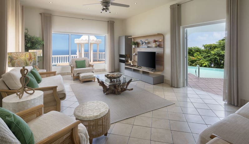 Royal Manor Spacious Luxury beach resort living room with comfortable armchairs, television entertainment unit, tiled flooring, and direct outdoor pool deck access at Windjammers Landing by Kenwood travel