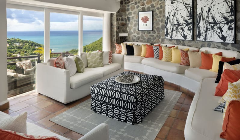 Dukes Manor Luxury oceanfront resort lounge area with plush couch seating, modern abstract artwork, stone wall architecture, and floor-to-ceiling sea view windows at Windjammers Landing by Kenwood travel