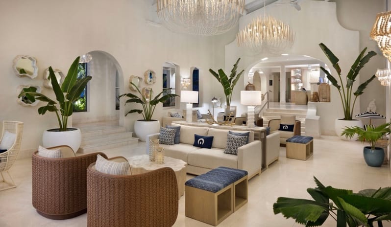 Dutchess Manor Bright and airy luxury resort lobby with modern woven armchairs, plush cream sofas, tropical potted plants, and ornate overhead chandeliers at Windjammers Landing by Kenwood travel