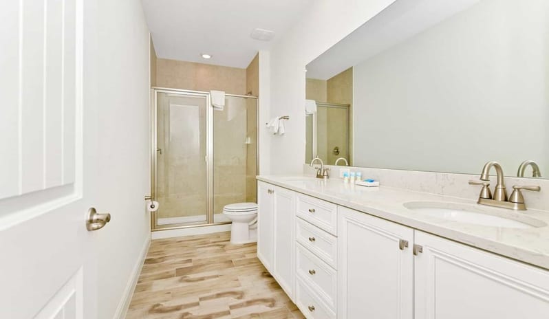 Four Bedroom Villa Bright master bathroom with double vanity sinks and a glass-enclosed shower at Margaritaville Resort Orlando by Kenwood Travel