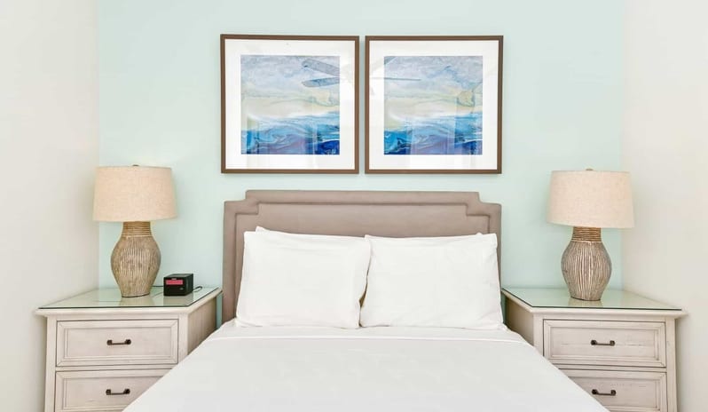 Four Bedroom Villa Bedroom with upholstered headboard flanked by white nightstands and bedside lamps at Margaritaville Resort Orlando by Kenwood Travel