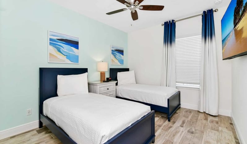 Four Bedroom Villa Coastal style guest bedroom with twin dark blue beds and a light blue accent wall at Margaritaville Resort Orlando by Kenwood Travel