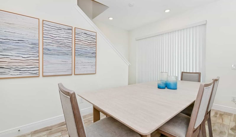 Four Bedroom Villa Modern dining table with grey chairs and abstract textured wall art at Margaritaville Resort Orlando by Kenwood Travel