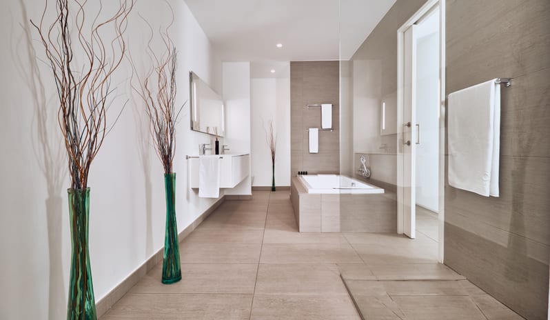 Divine Breeze Luxurious spa-style villa bathroom with a deep soaking bathtub, walk-in shower glass, floating double vanity, and plush white towels at Domes Baobab by Kenwood Travel