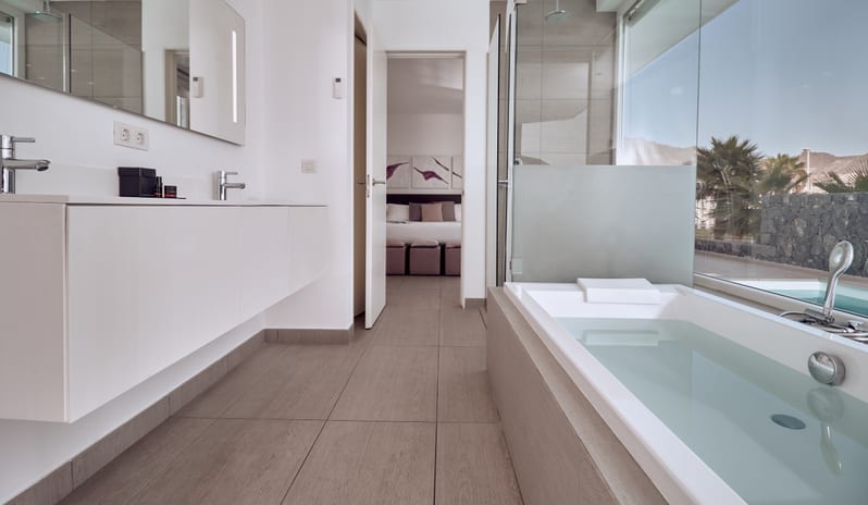 Divine Mar Modern white master bathroom with a deep soaking tub and floating vanity at Domes Baobab by Kenwood Travel