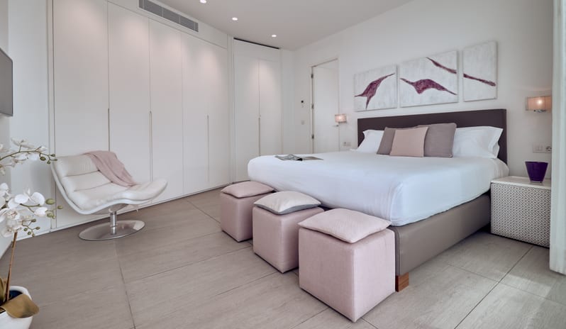 Divine Mar Minimalist master bedroom with plush white bedding and soft pink accent stools at Domes Baobab by Kenwood Travel