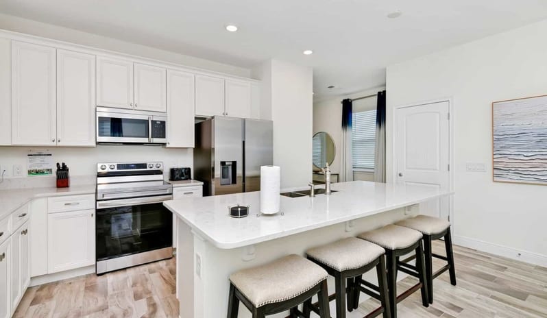 Margaritaville Resort Orlando - Four Bedroom Villa Bright white kitchen featuring a large island with barstool seating - Kenwood Travel
