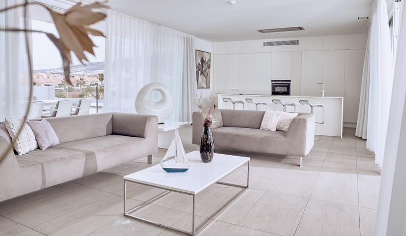 Serenity Allegra Spacious open-concept apartment interior with sleek white kitchen cabinets, breakfast bar barstools, and light grey tile flooring at Domes Baobab by Kenwood Travel