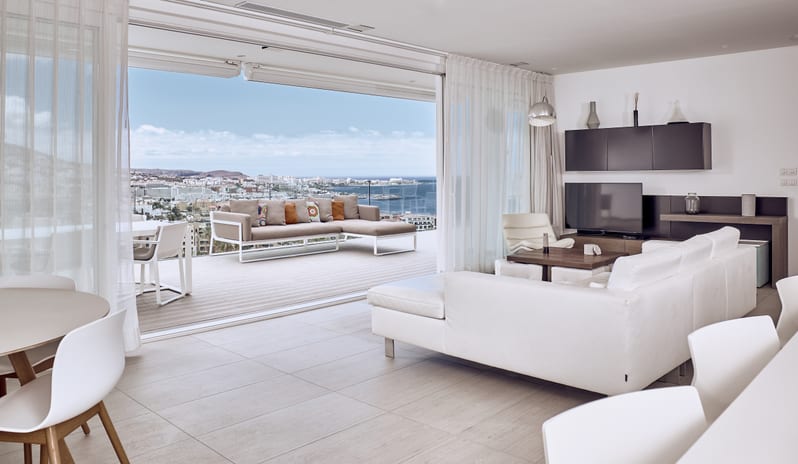 Serenity Essence Spacious luxury penthouse living area seamlessly connecting to a private sun terrace with outdoor couch and panoramic coastal city views at Domes Baobab by Kenwood Travel