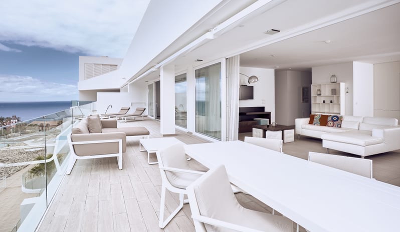 Serenity Essence Oceanfront villa patio equipped with a white outdoor dining setup, plush lounge furniture, and panoramic sea views at Domes Baobab by Kenwood Travel