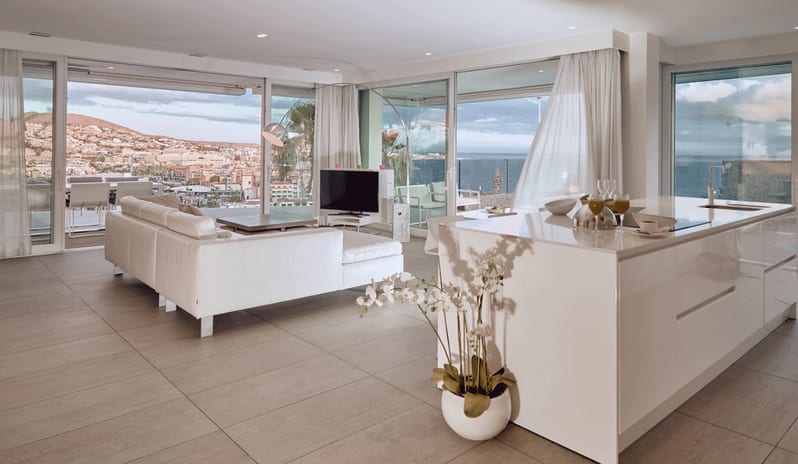 Serenity Elegance Contemporary white open-plan apartment with large sliding doors, white sofa, sleek kitchen island, and sweeping coastal landscape views at Domes Baobab by Kenwood Travel