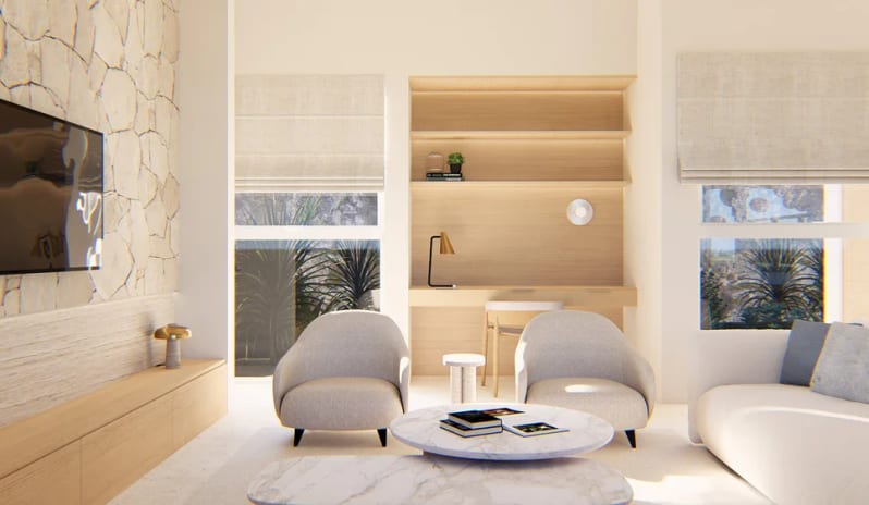 Hillside Penthouse Bright modern living room interior featuring two white armchairs, marble coffee tables, a built-in wooden desk and bookshelf unit, a TV on a stone accent wall, and large windows with outdoor views at The Calabash Hotel by Kenwood Travel