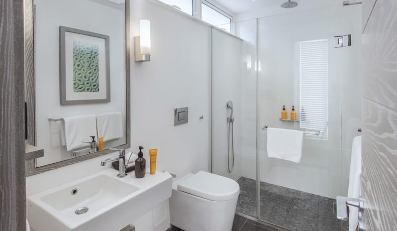 Family Suite bathroom featuring a modern vanity sink, mirror, toilet, and walk-in glass shower enclosure at Long Beach Mauritius by Kenwood Travel