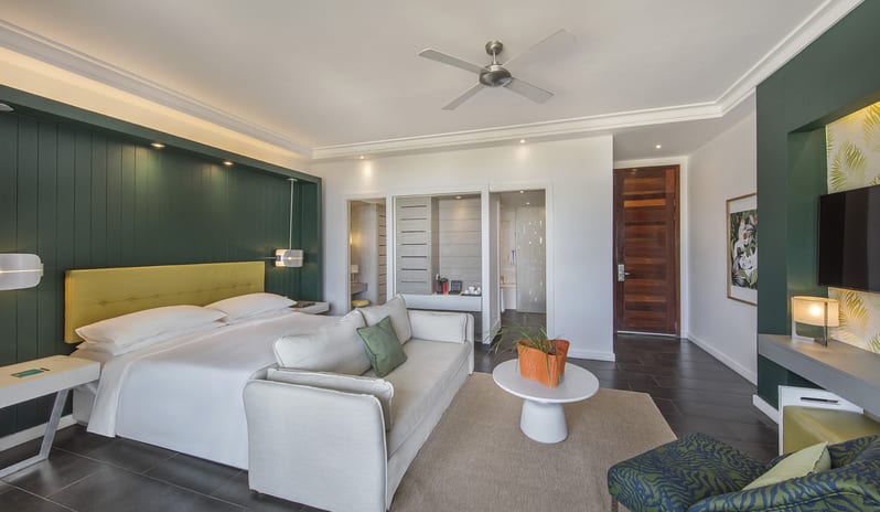 Junior Suite Beach Front king bed with yellow headboard, white sofa lounge, coffee table, and ensuite bathroom access at Long Beach Mauritius by Kenwood Travel