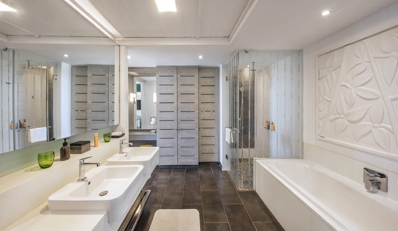 Junior Suite Beach Front bathroom featuring double sink vanity, large soaking bathtub, walk-in glass shower, and vanity mirrors at Long Beach Mauritius by Kenwood Travel