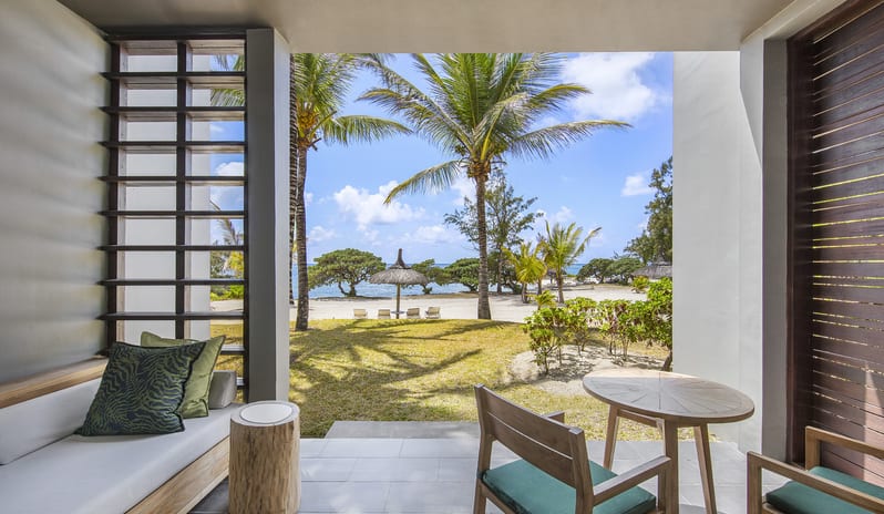 Junior Suite Beach Front private terrace featuring outdoor dining chairs, built-in daybed, and direct views of tropical gardens and sandy beach at Long Beach Mauritius by Kenwood Travel