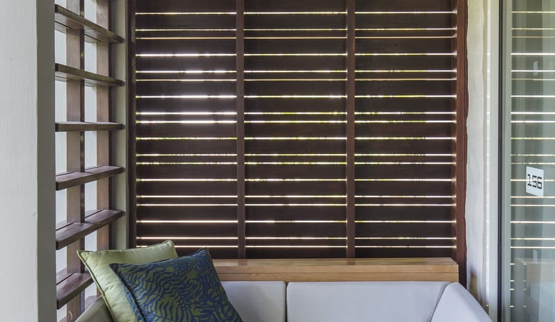 Junior Suite Premium lounge with comfortable cushions, wooden slatted privacy screen, and rustic tree trunk side table at Long Beach Mauritius by Kenwood Travel