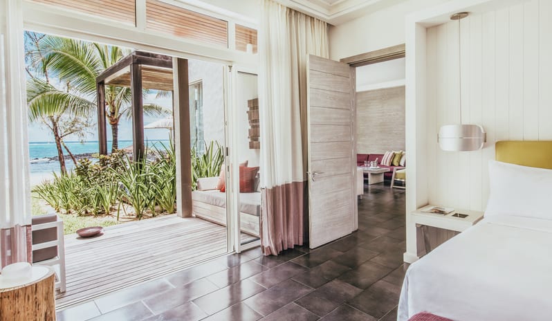 Long Beach Executive Suite king bed opening to a private wooden sun deck, outdoor lounge daybed, and ocean view at Long Beach Mauritius by Kenwood Travel