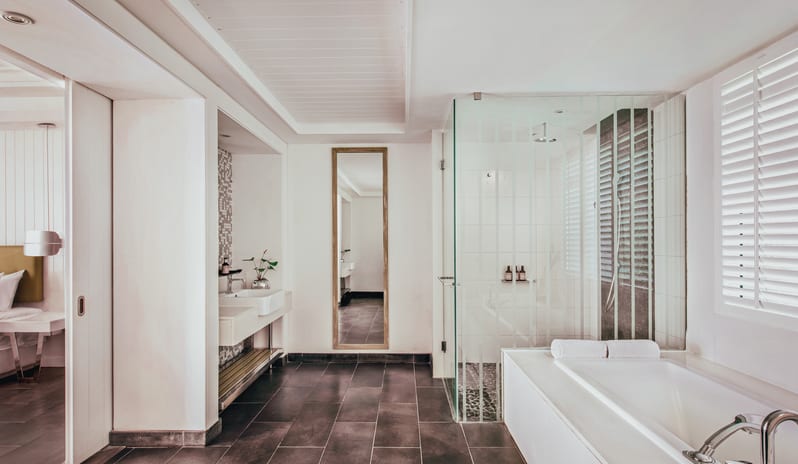 Long Beach Executive Suite bathroom featuring a deep soaking bathtub, glass walk-in shower cabin, vanity sink, and full-length dressing mirror at Long Beach Mauritius by Kenwood Travel