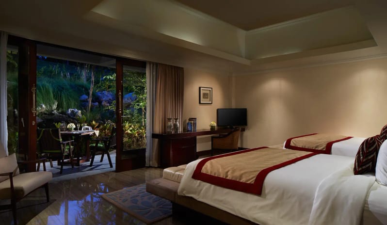 Royal Samabe Residence warm ambient lighting, desk console, armchair, and open sliding doors leading to a private outdoor garden dining patio at Samabe Bali Suites and Villas by Kenwood Travel