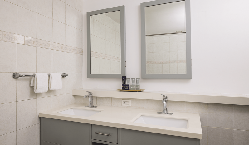 Club Room Garden View bathroom featuring a modern double sink vanity with dual framed mirrors, chrome faucets, and complimentary toiletries at St James’s Club & Villas by Kenwood Travel