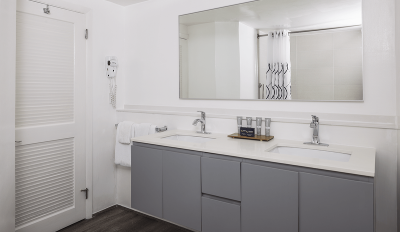 Premium Oceanview Partial Ocean View Modern ensuite bathroom in a premium king room with a gray double-sink vanity, large wall mirror, and toiletries tray at St James’s Club & Villas by Kenwood Travel