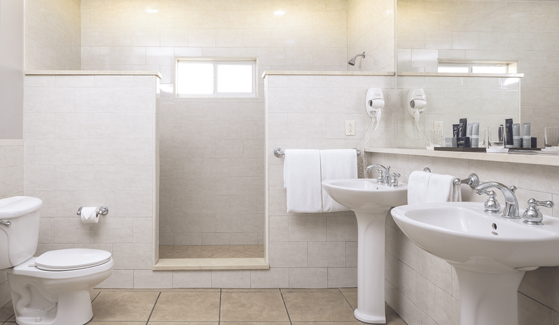 Royal Suite Bay View bathroom featuring tiled walls, dual pedestal sinks with chrome fixtures, a walk-in shower area, and complimentary bath amenities at St James’s Club & Villas by Kenwood Travel