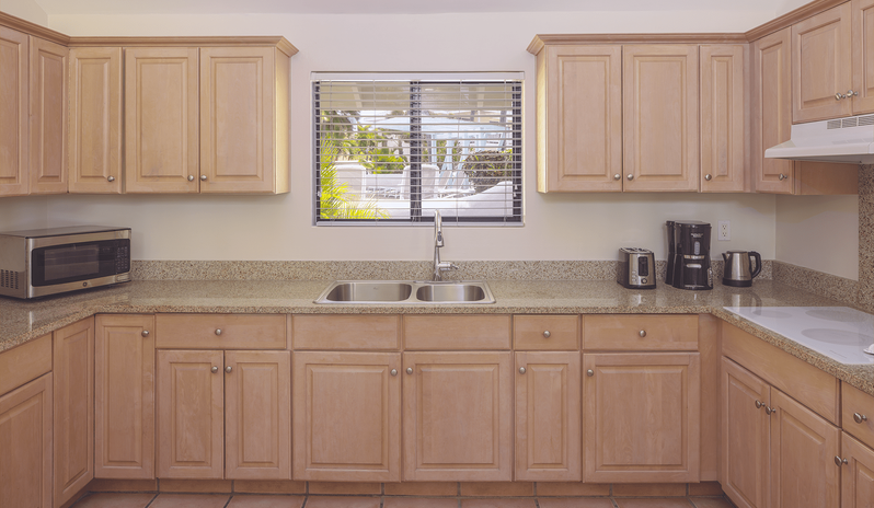 Two Bedroom Villa Fully equipped resort villa kitchen with natural light wood cabinets, granite countertops, double stainless steel sink, microwave, toaster, and coffee maker at St James’s Club & Villas by Kenwood Travel