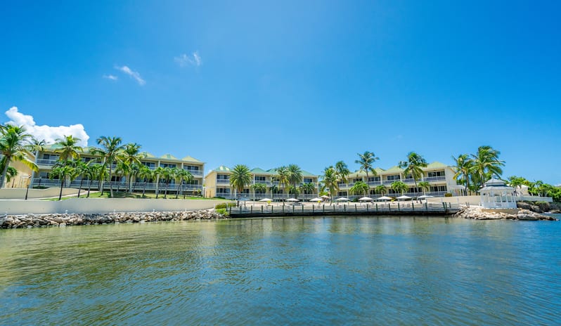 Royal Suite Bay View lined with tropical palm trees, a sun terrace deck, and a white gazebo overlooking clear blue water at St James’s Club & Villas by Kenwood Travel